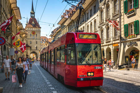 Bern Switzerland, June 27, 2020: Red tram going to Ostring and Kafigturm or prison tower with people...