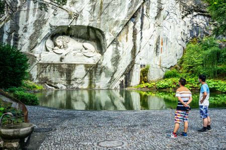Lucerne Switzerland, June 29, 2020: Two Asian tourists wearing surgical face masks looking at Lucerne Lion monument during summer 2020 and covid-19 crisis in Switzerlandのeditorial素材