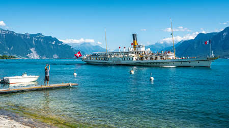 Vevey Switzerland, 4 July 2020: Tourist taking picture from lakeside of La Suisse a touristic vintage paddle steamboat sailing on Lake Geneva in Vevey Switzerlandのeditorial素材