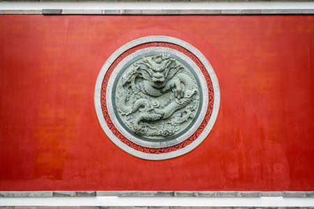 Red wall with dragon circular sculpture at the Confucian temple of Dali old town in Dali Yunnan Chinaの写真素材