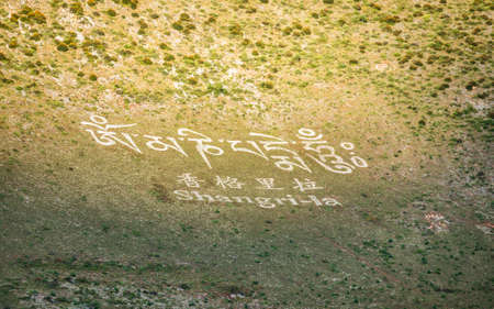 Shangri-La city sign with name written on mountainside in English Chinese characters and Tibetan...