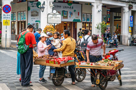 Haikou China, 21 March 2021: Chinese tourists buying exotic fruits from local peoples hawking in the street of Haikou old town Hainan Chinaのeditorial素材
