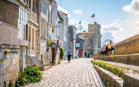28 July 2021, La Rochelle France: Beautiful view of the Chain and Saint Nicolas Towers and Sur-Les-Murs medieval street and tourists in La Rochelle historic center Franceのeditorial素材