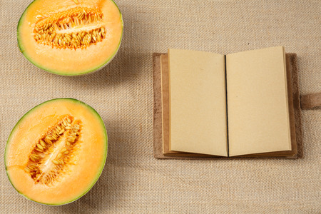 Melon and Opened Notebook lying on a sackcloth surface