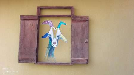 Wooden window with colorful goat painting on the wall of the houseの写真素材