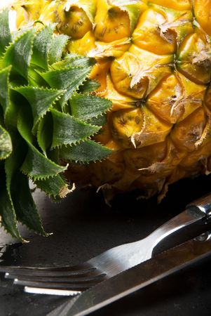 ripe pineapple on a black plate with knife and forkの写真素材