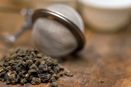 dry green chinese tea set,with strainer closeup,cups and teapot on background over old wood boardの写真素材