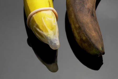 two bananas one good with condom one rotten without condom safe sex conceptの写真素材