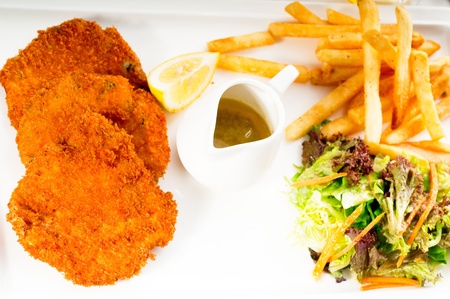 classic breaded Milanese veal cutlets with french fries and vegetables on backgroundの写真素材