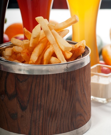 fresh french fries on a wood bucket with selection of beers and fresh vegetables on backgroundの写真素材