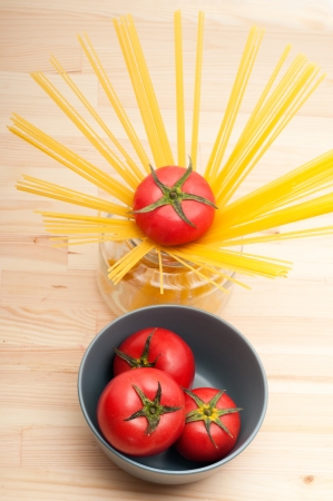 fresh tomato and raw spaghetti pasta over pine wood tableの写真素材