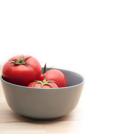 fresh ripe tomatoes on a blue bowl over pine wood tableの写真素材