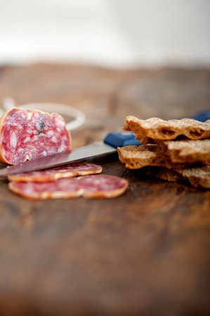 slicing italian salame pressato pressed over old wood tableの写真素材