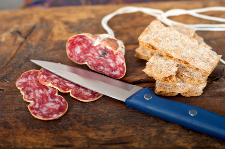 slicing italian salame pressato pressed over old wood tableの写真素材