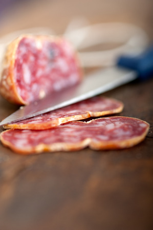 slicing italian salame pressato pressed over old wood tableの写真素材