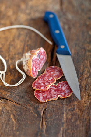 slicing italian salame pressato pressed over old wood tableの写真素材