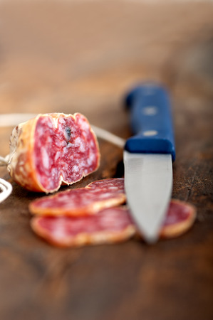slicing italian salame pressato pressed over old wood tableの写真素材