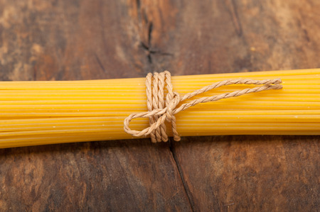 Italian pasta spaghetti tied with a rope on a rustic tableの写真素材