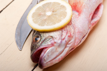 fresh whole raw fish on a wooden table ready to cookの写真素材