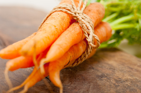 fresh baby carrots bunch tied with rope on a rustic tableの写真素材