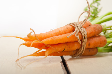 fresh baby carrots bunch tied with rope on a rustic tableの写真素材