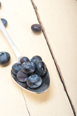 fresh blueberry on silver spoon over a white rustic wood tableの写真素材