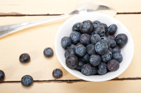 fresh blueberry on a bowl with silver spoon over wood tableの写真素材