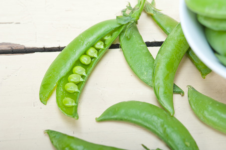 hearthy fresh green peas  over a rustic wood table