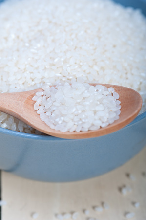 raw white rice on wood spoon and blue bowl extreme close upの写真素材