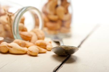 cashew nuts on a glass jar over white rustic wood tableの写真素材