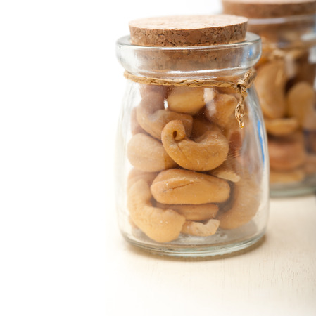 cashew nuts on a glass jar over white rustic wood tableの写真素材
