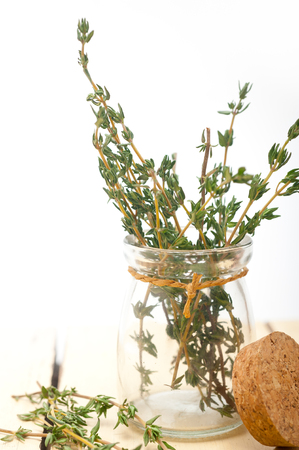 fresh thyme on a glass jar over a white wood rustic tableの写真素材