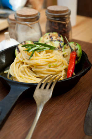 italian spaghetti pasta with zucchini sauce on iron skillet over wood boardの写真素材