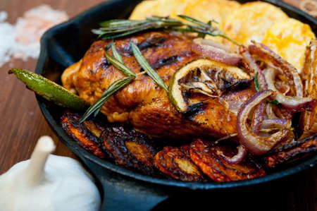 roasted grilled BBQ chicken breast with herbs and spices rustic style on iron skillet