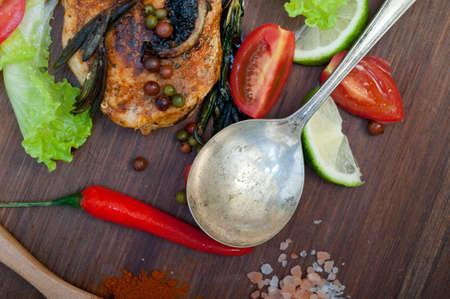 wood fired hoven cooked chicken breast on wood board with herbs spices and vegetablesの写真素材