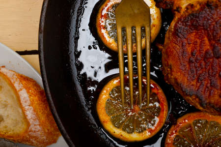 pork chop seared on iron skillet with lemon and spices seasoningの写真素材