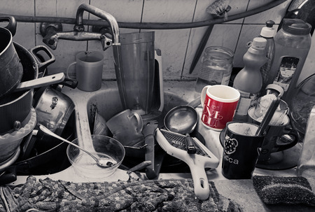 Pile of dirty utensils in a kitchen washbasin and a red mug with an I Love You textの写真素材