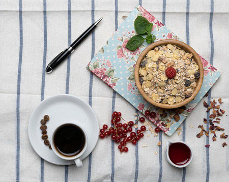 Healthy breakfast with muesli, raspberry, cherries and coffee on a background of white tablecloth,...