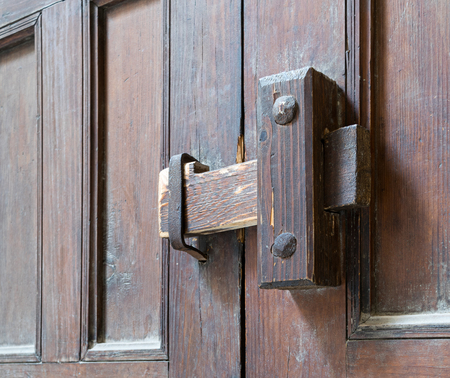 Closeup of a wooden aged latch over an ornate wooden doorの写真素材