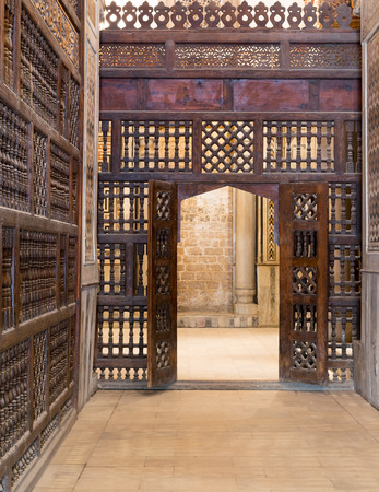 Interleaved wooden wall (mashrabiya) with wooden ornate door in Sultan Qalawun mosque, a historic mosque in Old Cairo, Egyptの写真素材