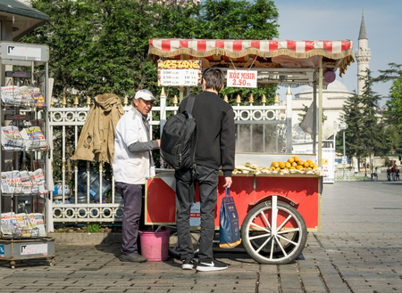 Istanbul, Turkey - April 16, 2017: Tourist buying fast food meal from a traditional Turkish chestnut and corn cart in Sultan Ahmed Squareのeditorial素材