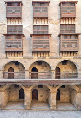 Facade of caravansary (Wikala) of Bazaraa, with vaulted arcades and windows covered by interleaved wooden grids (mashrabiyya), suited in Tombakshia street, Al Gamalia district, Medieval Cairo, Egyptの写真素材