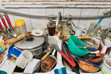 Pile of dirty utensils in a kitchen washbasin