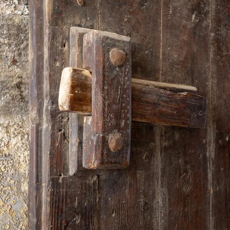 Angled view closeup of a wooden aged latch over a wooden opened door