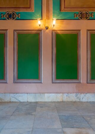 Beautiful elegant carved green frames on orange wall with ornate border and white marble tiled floor, in abandoned old buildingの写真素材