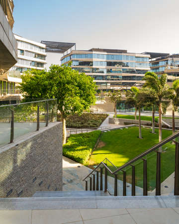 Marble staircase and glass handrail leading to street in contemporary urban city district with well...