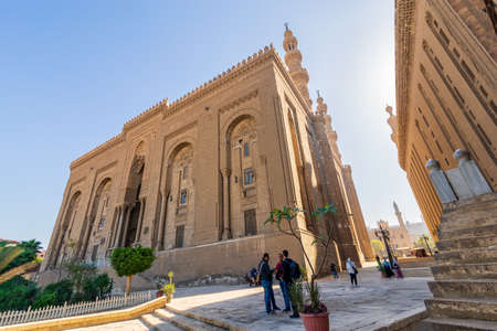 Cairo, Egypt - November 27 2021: Facade of Islamic Royal era Mosque of Al Rifai, with side view of Mamluk era Mosque and Madrassa of Sultan Hassan, with few visitors, Old Cairoのeditorial素材
