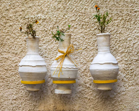 Three adjacent handmade white pottery vases, arabic: Kolla, hanged on rough stone white wallの写真素材
