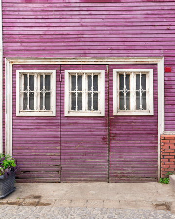 Wooden grunge weathered abandoned door painted in purple, with three white wooden windows painted in white, in a cobblestone alleyの写真素材