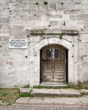 Arched entrance with open green metal door in brick stone wall leading to 16th century Atik Valide Mosque in Uskudar district, Istanbul, Turkeyの写真素材